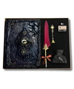 Coffret cadeau avec grimoire gothique à l'œil de dragon blanc, plume d'écriture bordeaux et kit de calligraphie vintage sur une table en bois avec roses.