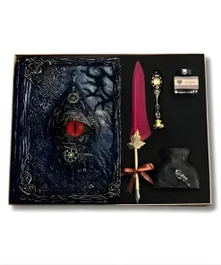 Coffret cadeau avec grimoire gothique à l'œil de dragon rouge, plume d'écriture bordeaux et kit de calligraphie vintage sur une table en bois avec roses.
