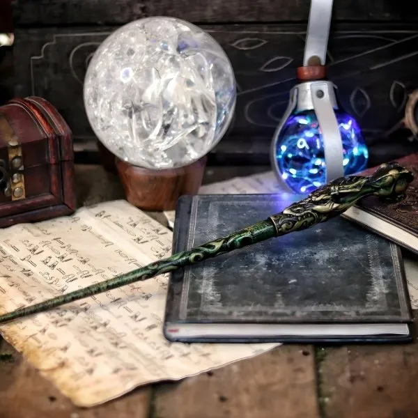 Autel de divination avec boule de cristal, grimoire ancien, fiole de potion lumineuse et baguette magique verte.