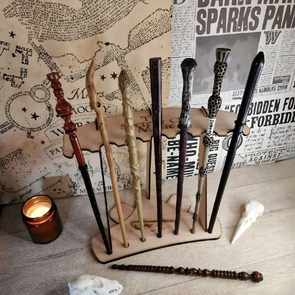 Collection de répliques de baguettes magiques Harry Potter exposées sur un présentoir en bois vertical, incluant les baguettes de Sureau, Lord Voldemort et Hermione Granger, devant une carte du Maraudeur.