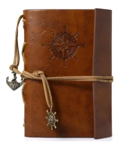 Carnets de voyage cuir marron vintage, rose des vents et breloques nautiques.