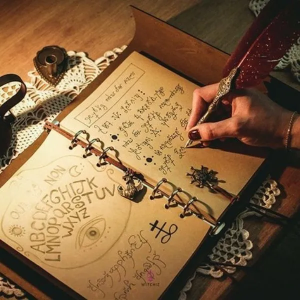 Une main de femme écrivant à la plume rouge dans un grimoire ancien relié en cuir, entourée de symboles ésotériques, d'un alphabet mystique et d'un œil dessiné.