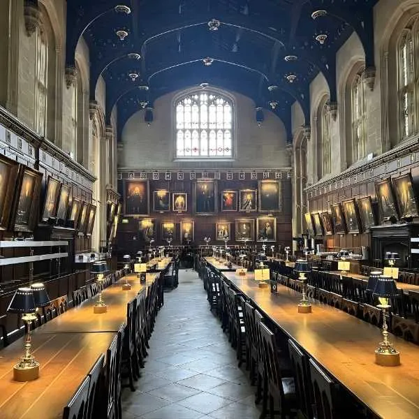 Tables de la Grande Salle de Poudlard avec vaisselle en or et architecture gothique.