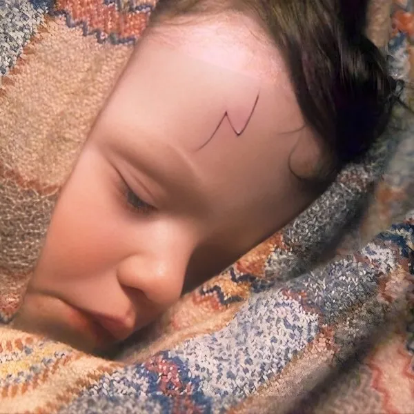 Gros plan du bébé Harry Potter endormi dans une couverture, révélant sa célèbre cicatrice en forme d'éclair sur le front.