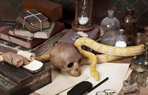 Nature morte mystérieuse sur un bureau d'alchimiste avec un crâne humain, un serpent jaune, des vieux grimoires reliés, un sablier et des fioles en verre aux studios Warner Bros.