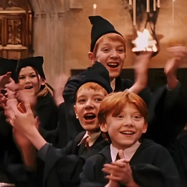 Ron Weasley avec Fred et George Weasley en robe de sorcier Gryffondor applaudissant dans la Grande Salle de Poudlard