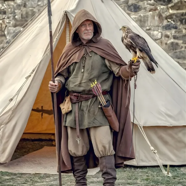 Homme en costume de fauconnier médiéval avec un rapace sur le poing devant une tente de campement historique