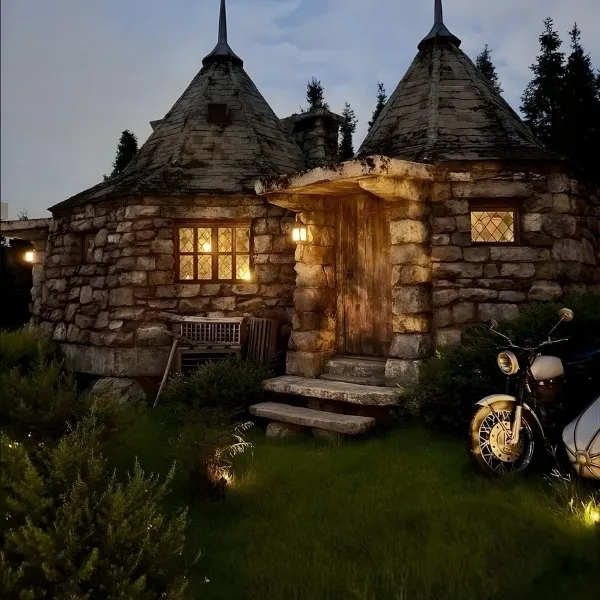 Reproduction fidèle de la cabane de Hagrid en pierre avec la moto de Sirius Black devant l'entrée, ambiance nocturne magique inspirée de l'univers Harry Potter.