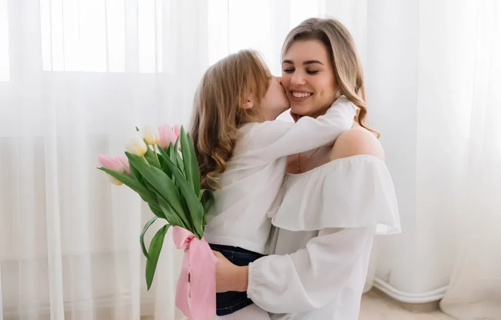 Petite fille embrassant sa maman et lui offrant un bouquet de tulipes pour la fête des mères