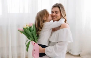 Petite fille embrassant sa maman et lui offrant un bouquet de tulipes pour la fête des mères