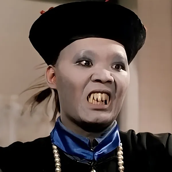 Maquillage de Jiangshi vampire sauteur chinois avec crocs apparents, peau blanche et costume traditionnel mandarin.
