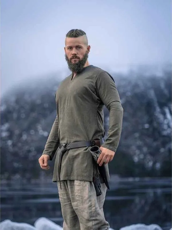 Homme barbu portant une tunique viking vert olive dans un paysage hivernal