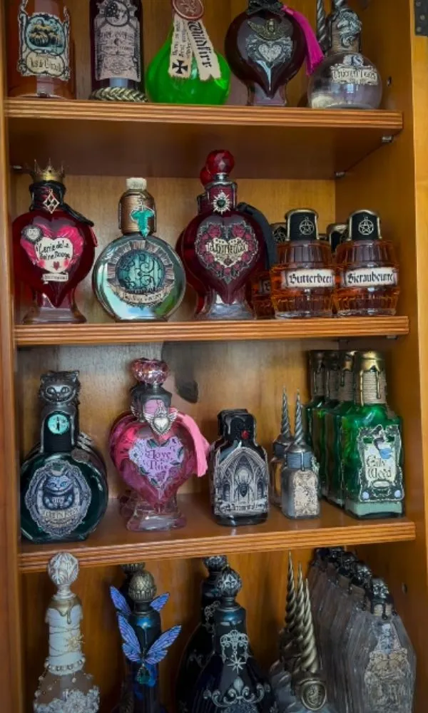 Fioles de potions magiques artisanales en forme de cœur alignées sur une étagère en bois.