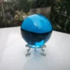 Boule de cristal azur mystique, 100mm, inclusions, posée sur socle en verre.