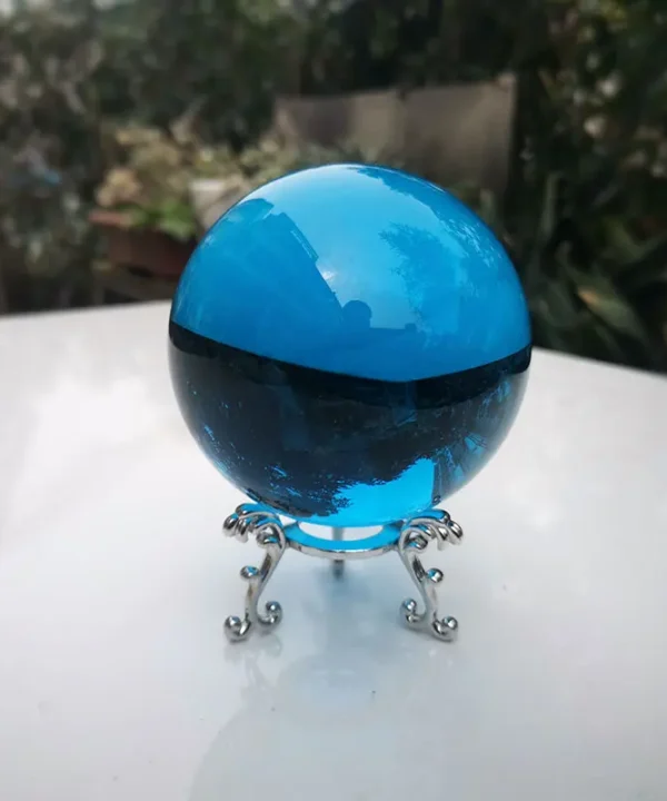 Boule de cristal azur mystique, 100mm, inclusions, posée sur socle en verre.