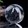 Boule de cristal céleste en quartz blanc naturel poli, inclusions et base.