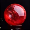 Boule de cristal écarlate en quartz naturel poli, rouge intense sur socle en bois.