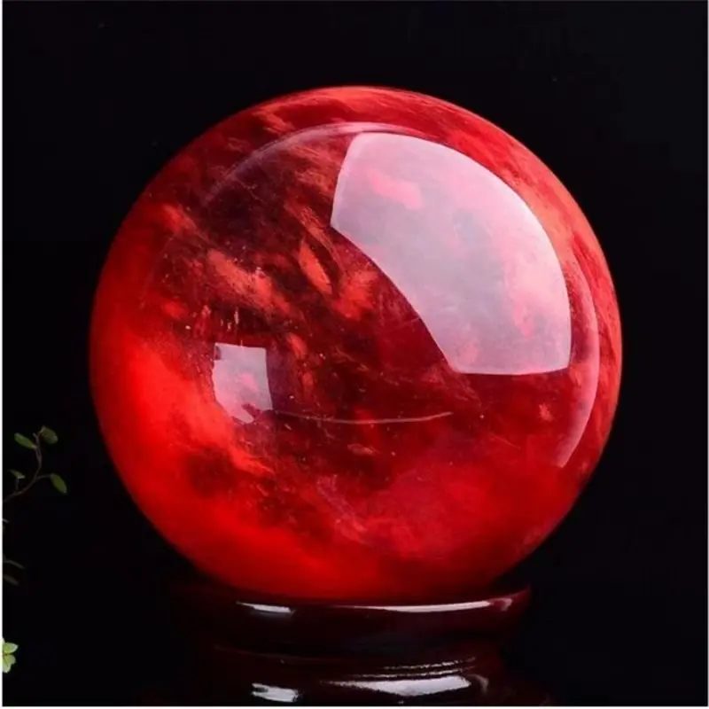 Boule de cristal écarlate en quartz naturel poli, rouge intense sur socle en bois.
