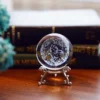 Boule de cristal K9 transparente, constellations Zodiaque 3D, support métallique argenté stylisé.